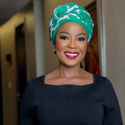 Wabo Majavu Smiling in Headwrap and Black Top
